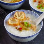 a bowl of plain congee with toppings like fried dough, preserved mustard stem and pork floss