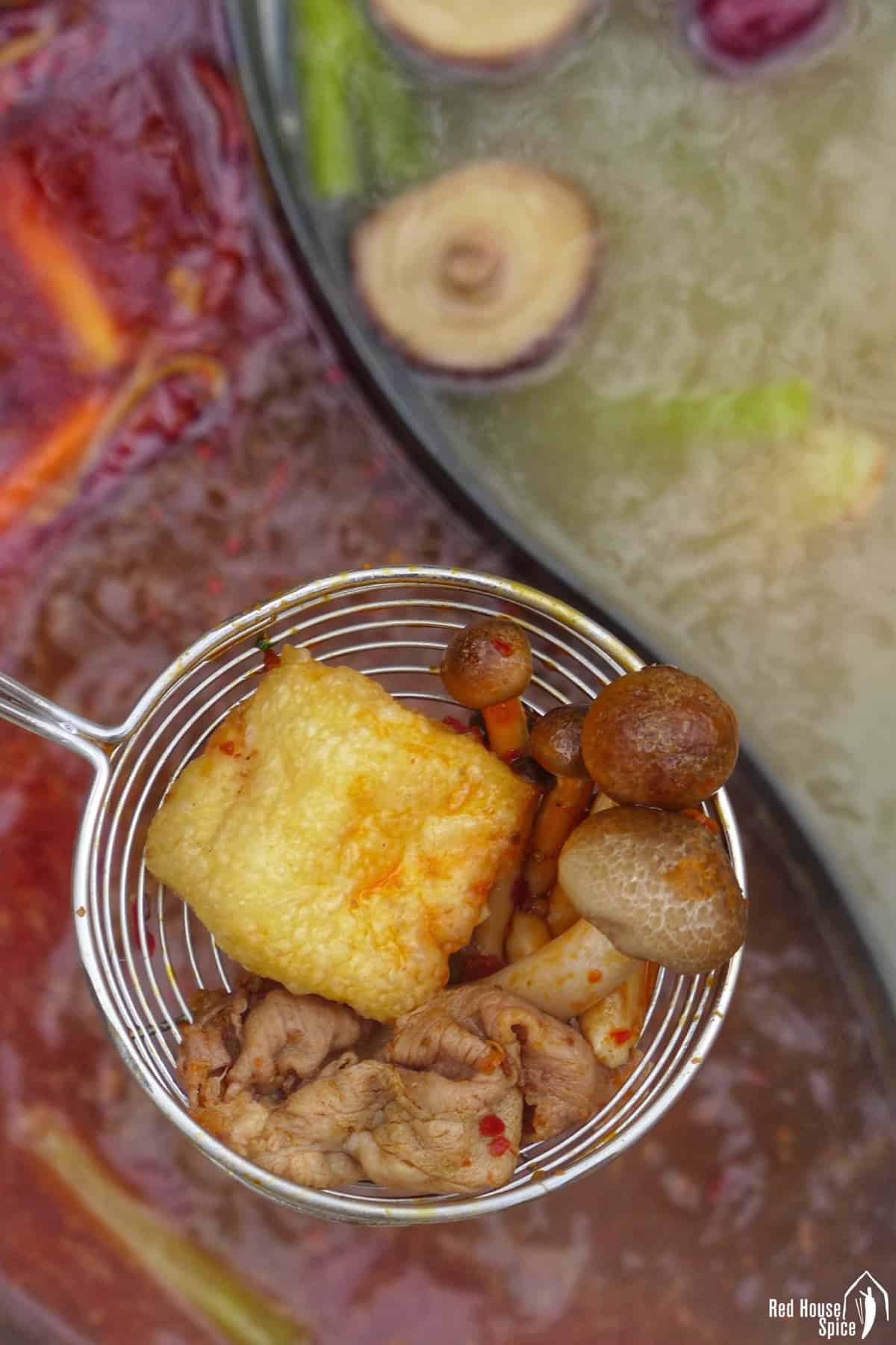 cooked tofu puff, mushroom and beef in a slotted ladle