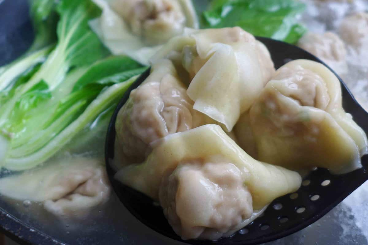 four cooked wontons in a spoon.