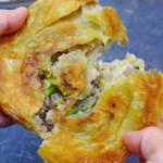 A crispy stuffed flatbread torn into halves.