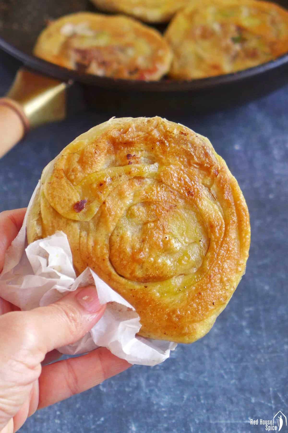 A Chinese crispy beef flatbread held by a hand.