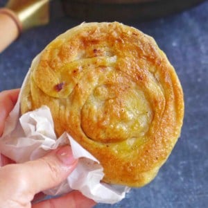 A Chinese crispy beef flatbread held by a hand.