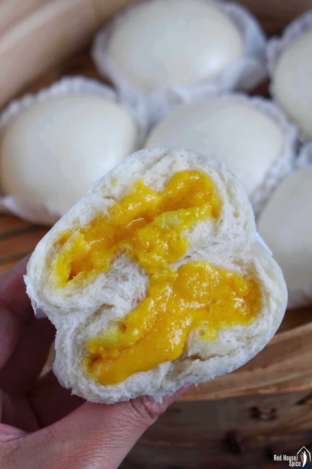 A halved custard bun held by a hand