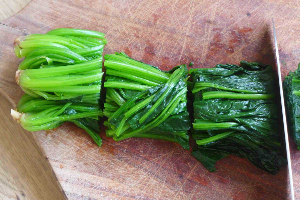 cutting blanched spinach into sections.
