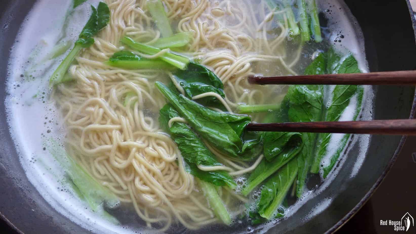 Noodles and green vegetable boiled in water.