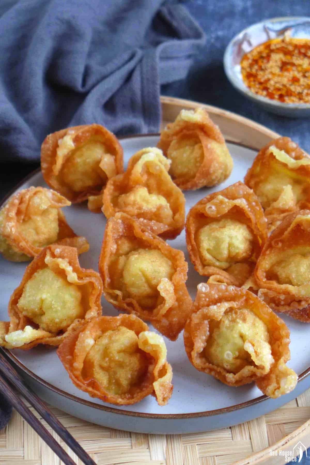 deep-fried wontons on a plate with chili oil on the side.