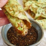 dipping a zucchini pancake into sauce.