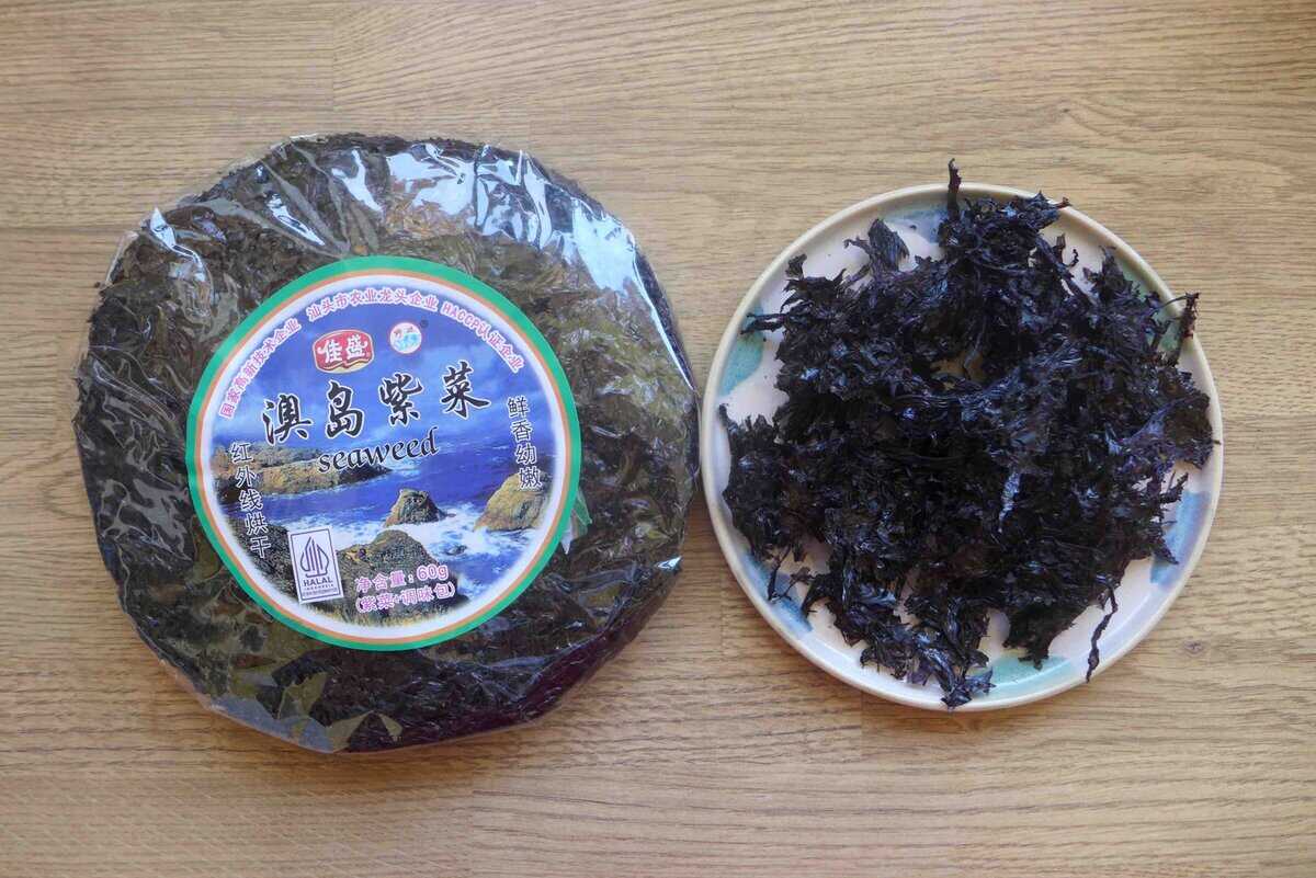 dried laver seaweed in package and torn pieces on a plate.