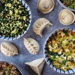 Four bowls of different dumpling fillings and some dumplings in different shape.