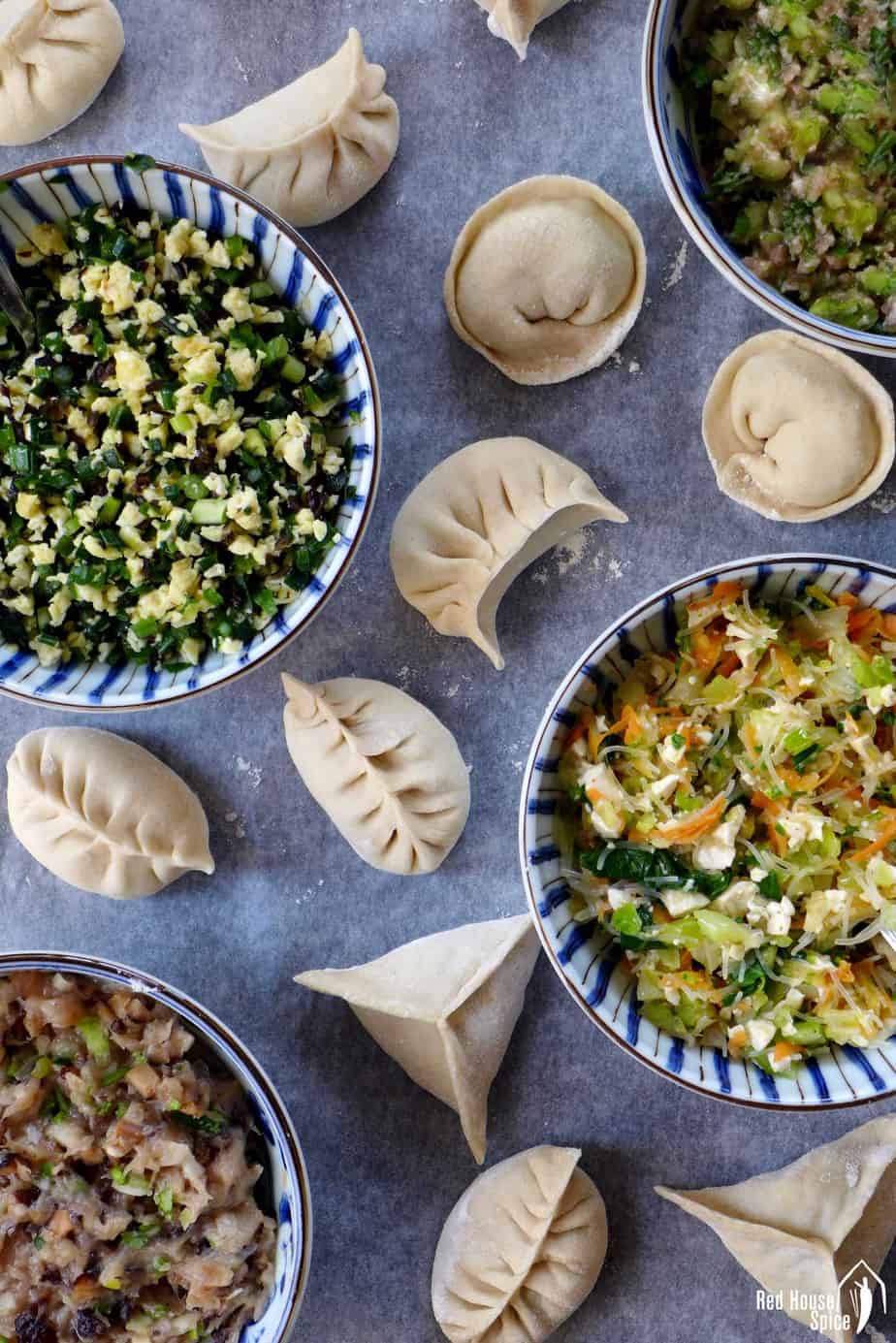 Four bowls of different dumpling fillings and some dumplings in different shape.