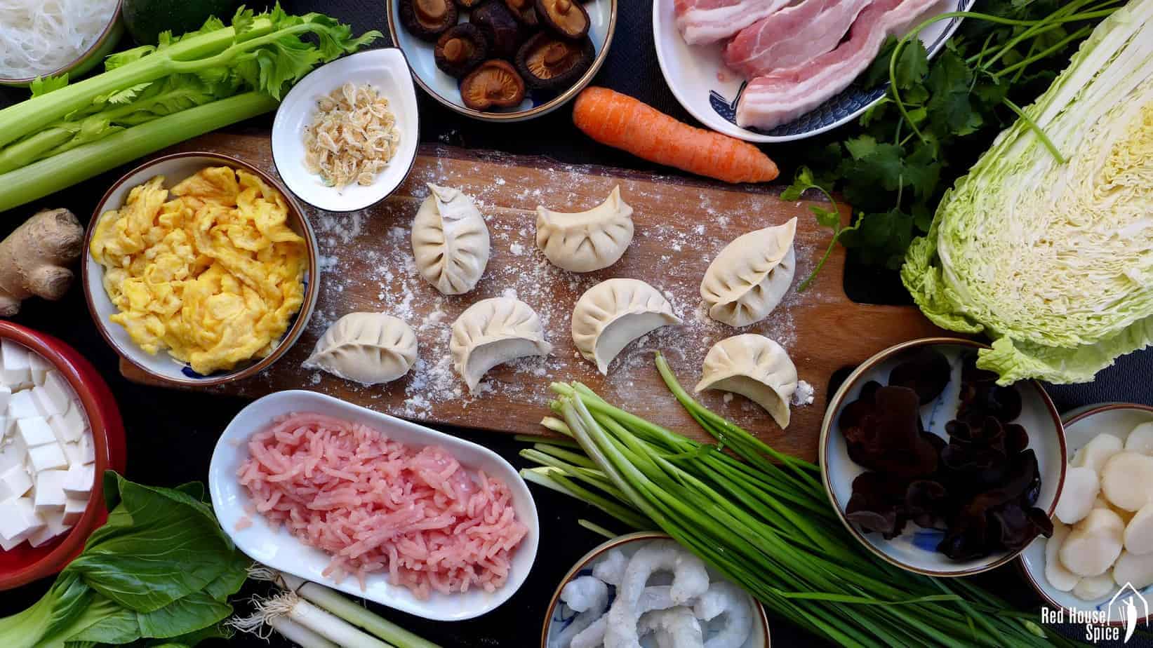 Dumplings surrounded by and raw ingredients for making dumpling fillings