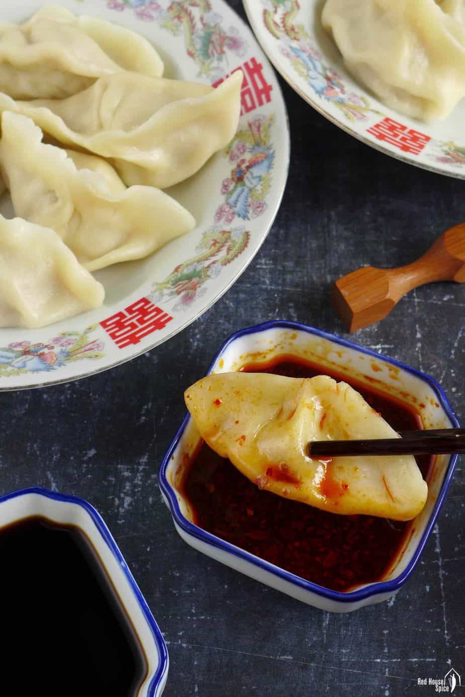 a boiled dumpling in chili dipping sauce