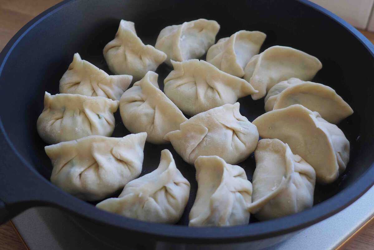 uncooked dumplings in a skillet.