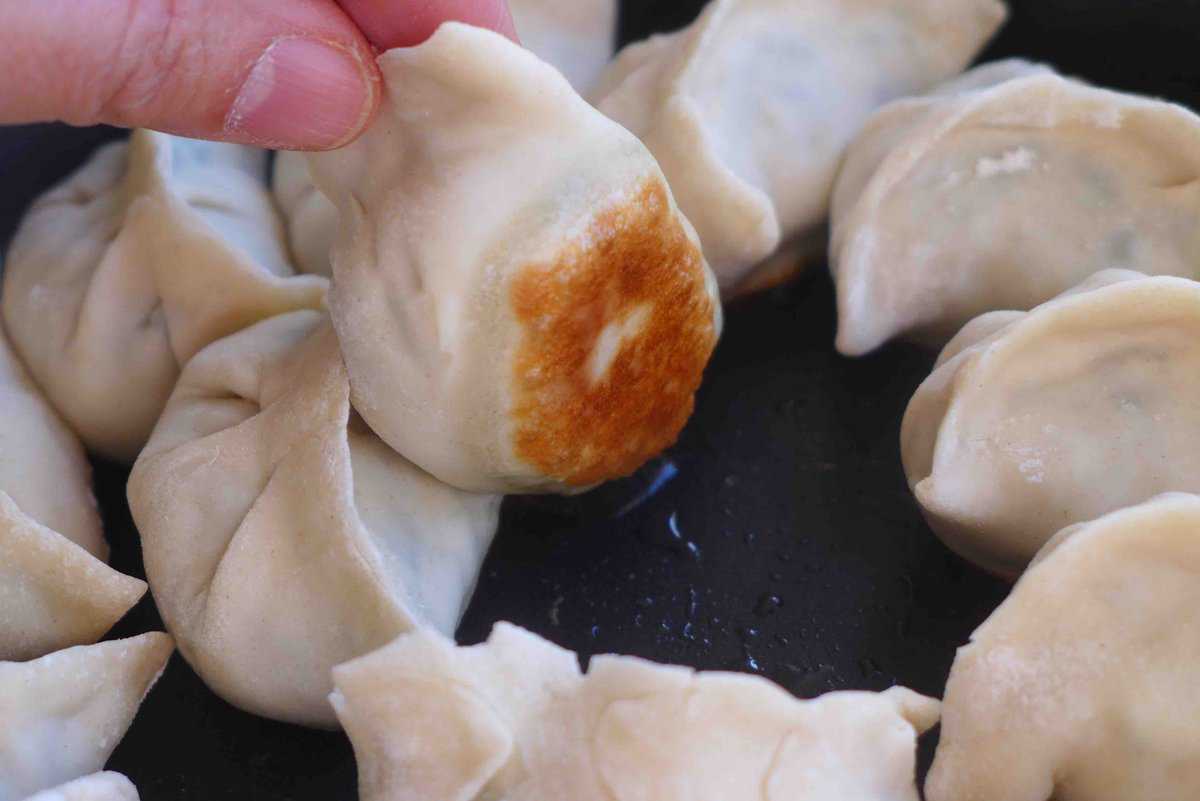 dumpling lifted by hand showing its golden bottom.