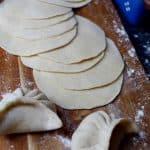 Freshly rolled dumpling wrappers and two dumplings.