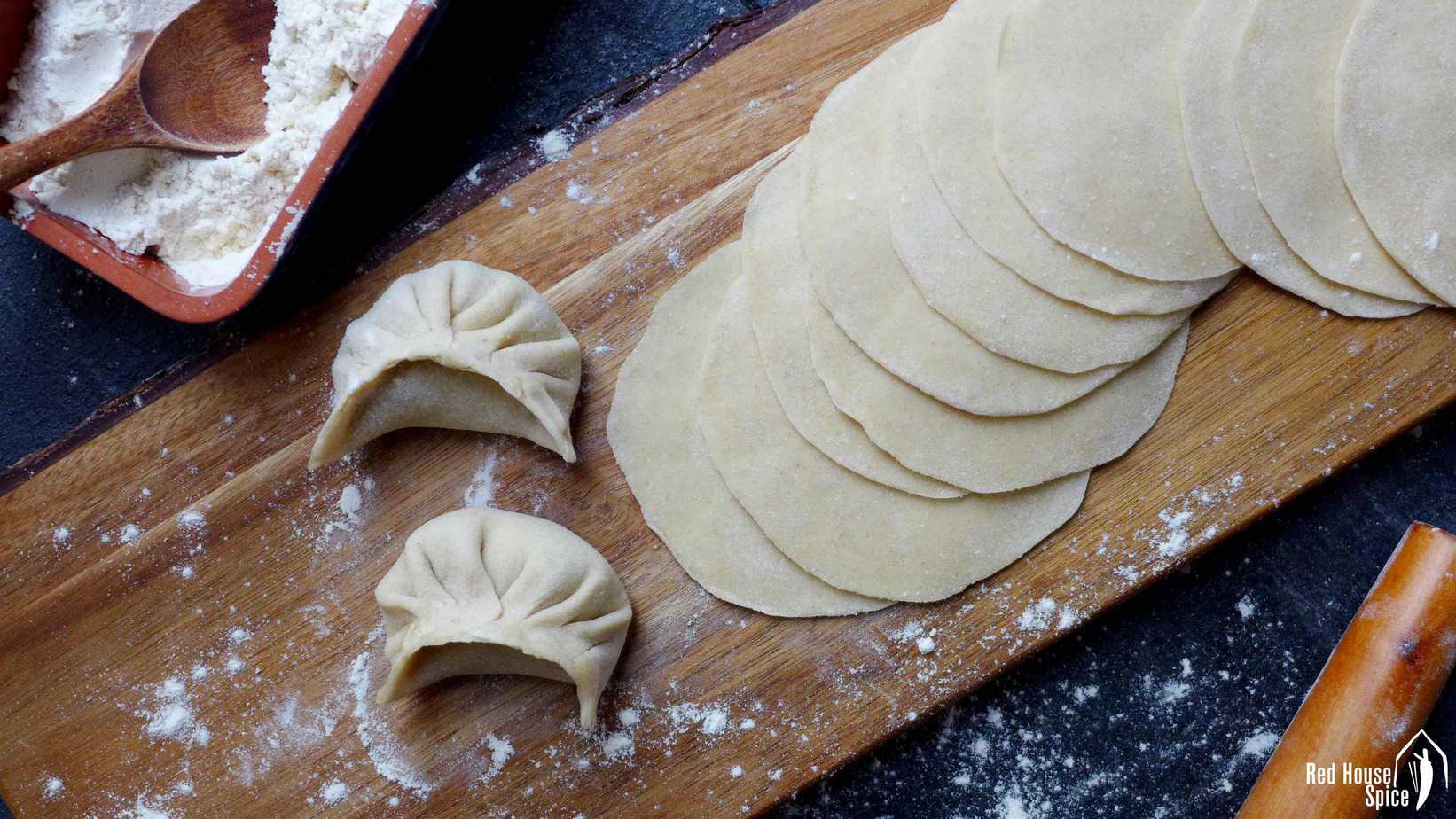 Freshly rolled dumpling wrappers and two dumplings.