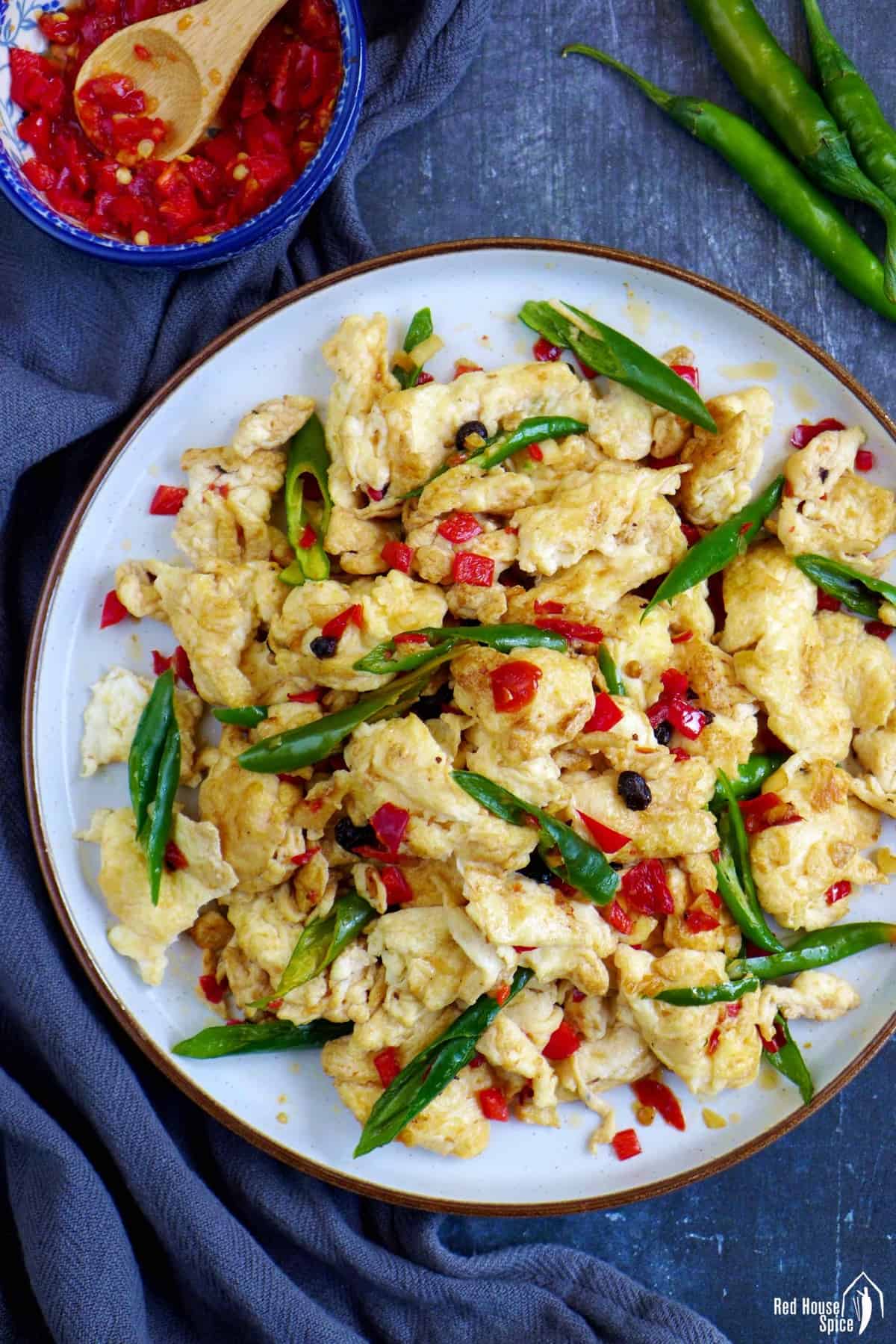 A plate of stir-fried egg with pickled chili and fresh chili