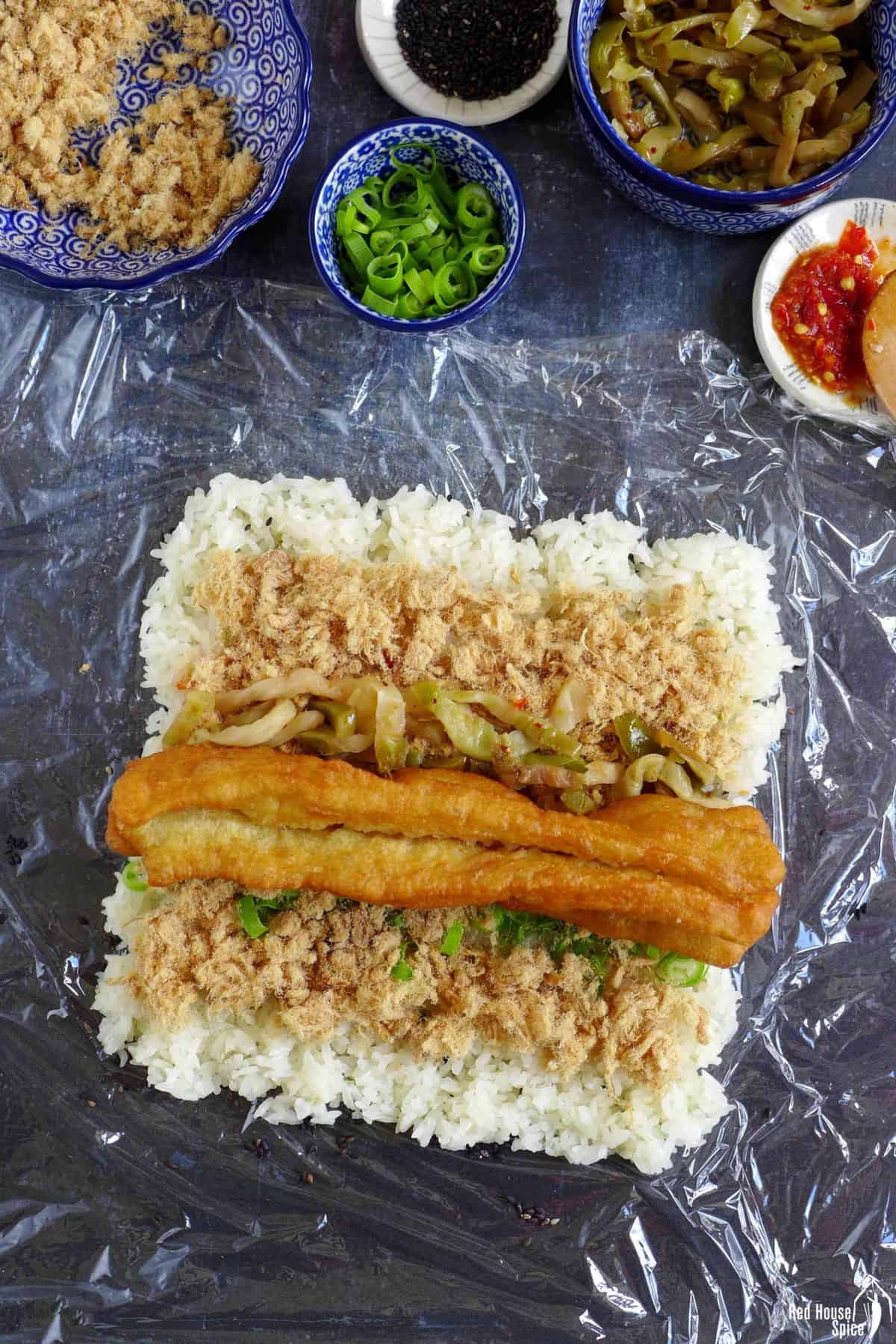 A Chinese doughnut stick, pork floss and preserved vegetable over a layer of rice.