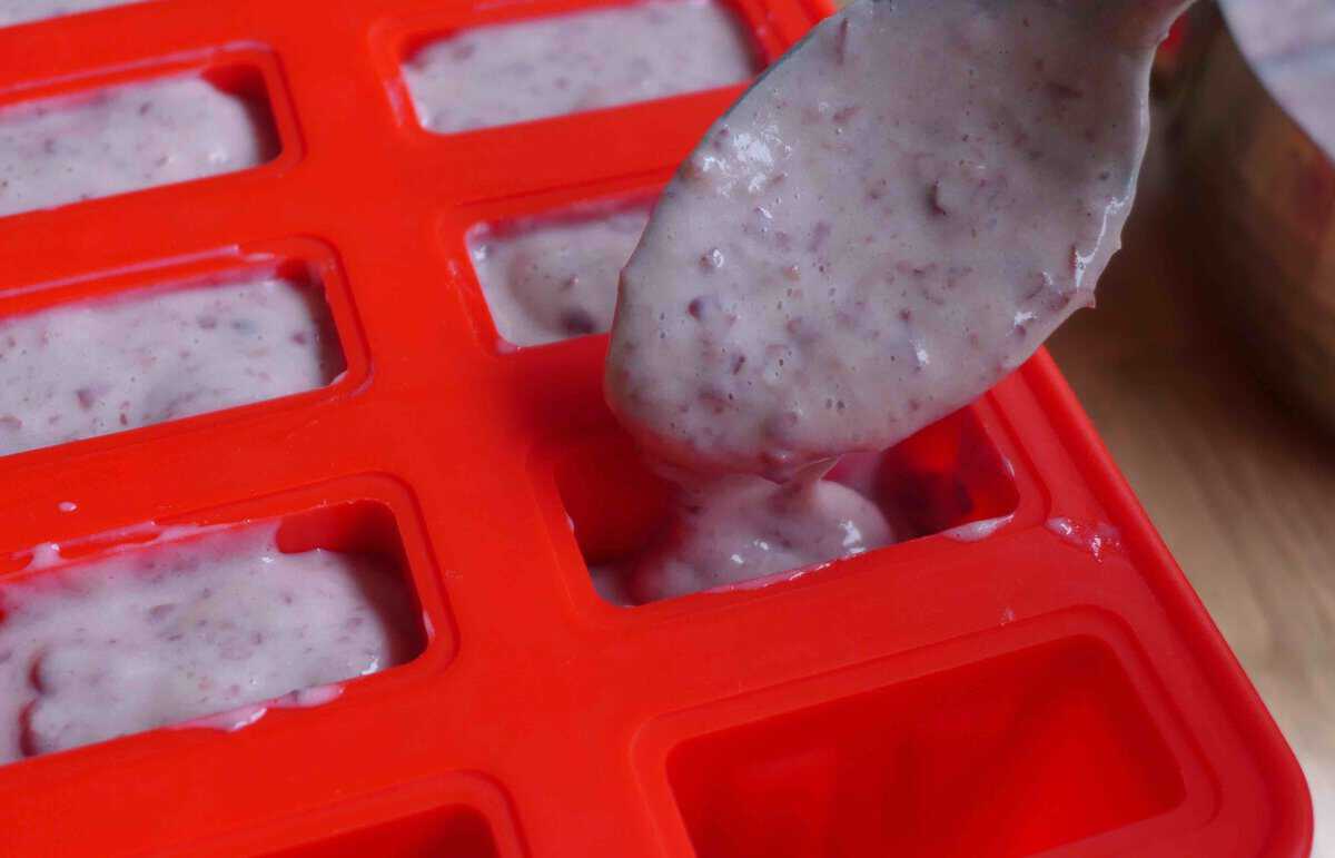 spooning red bean popsicle mixture into a mold.