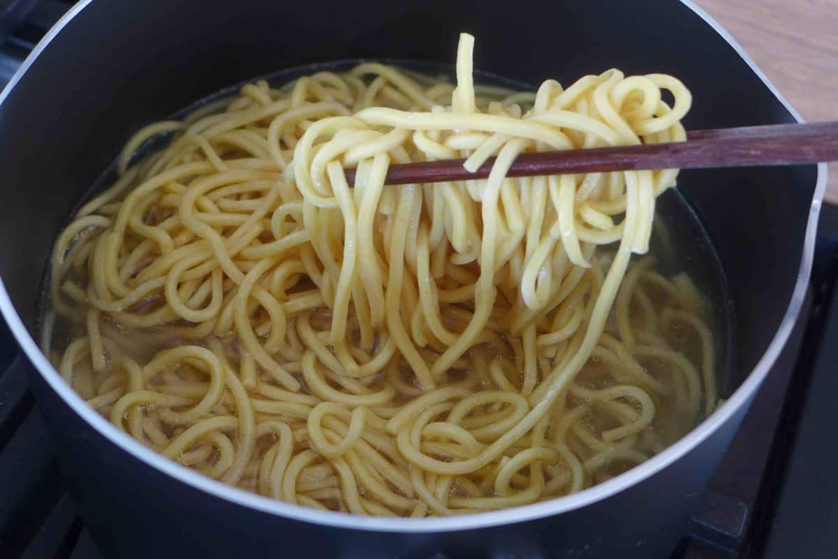 fishing noodles out of water with chopsticks.