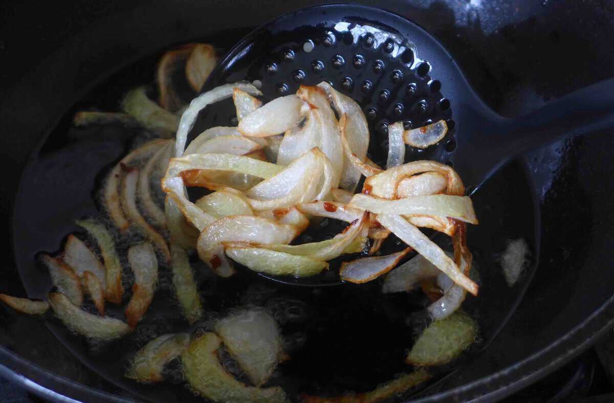 fishing out fried onion out of oil.