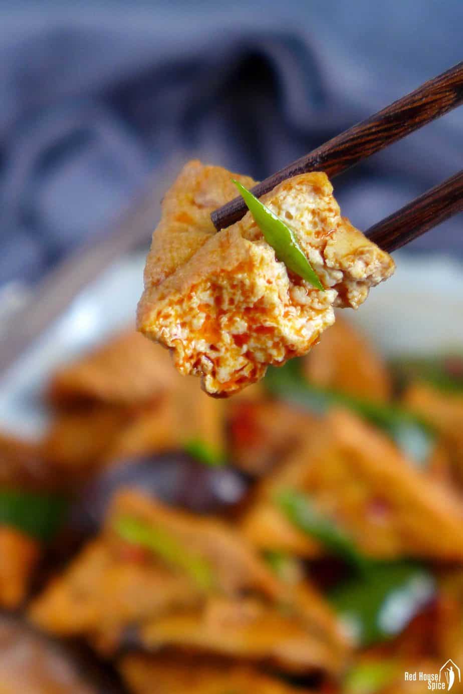 chopsticks picking up a piece of fried tofu