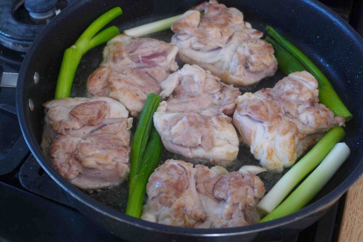 pan-frying chicken thighs with scallions.