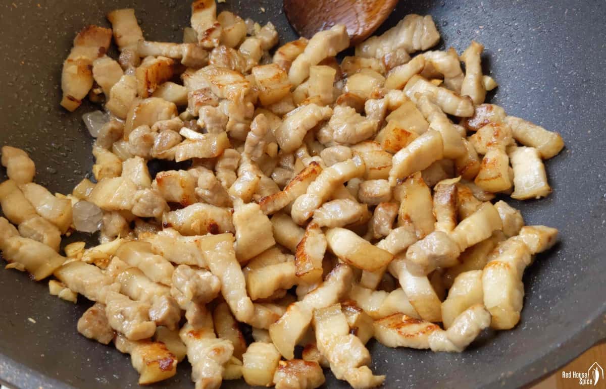 frying pork belly strips in a wok