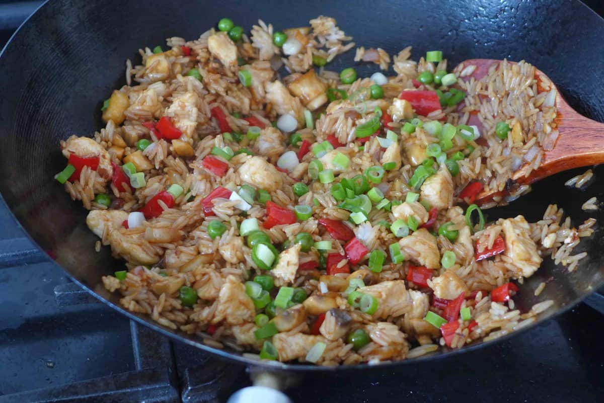 stir-frying chicken with vegetables and rice.