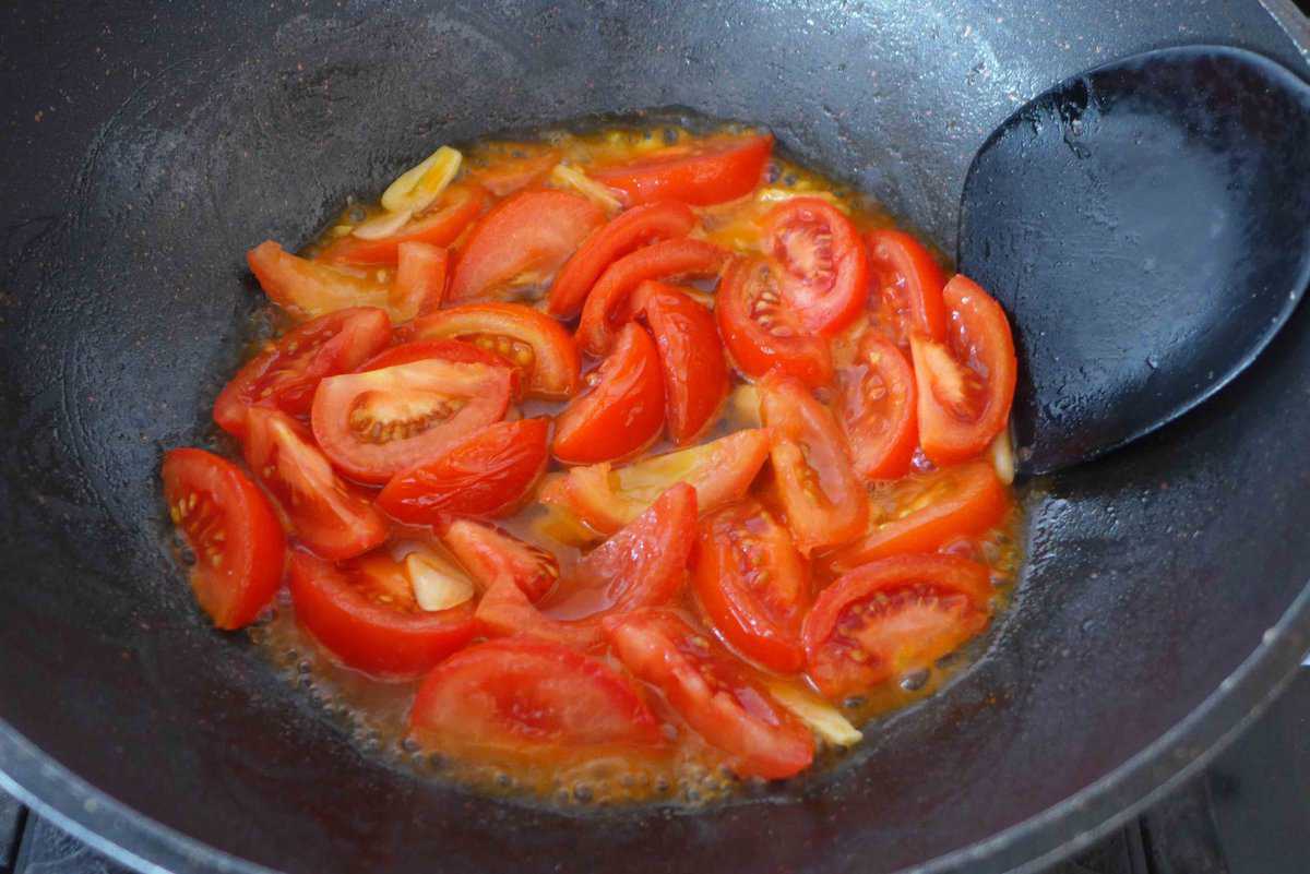 cooking tomato wedges in a wok.