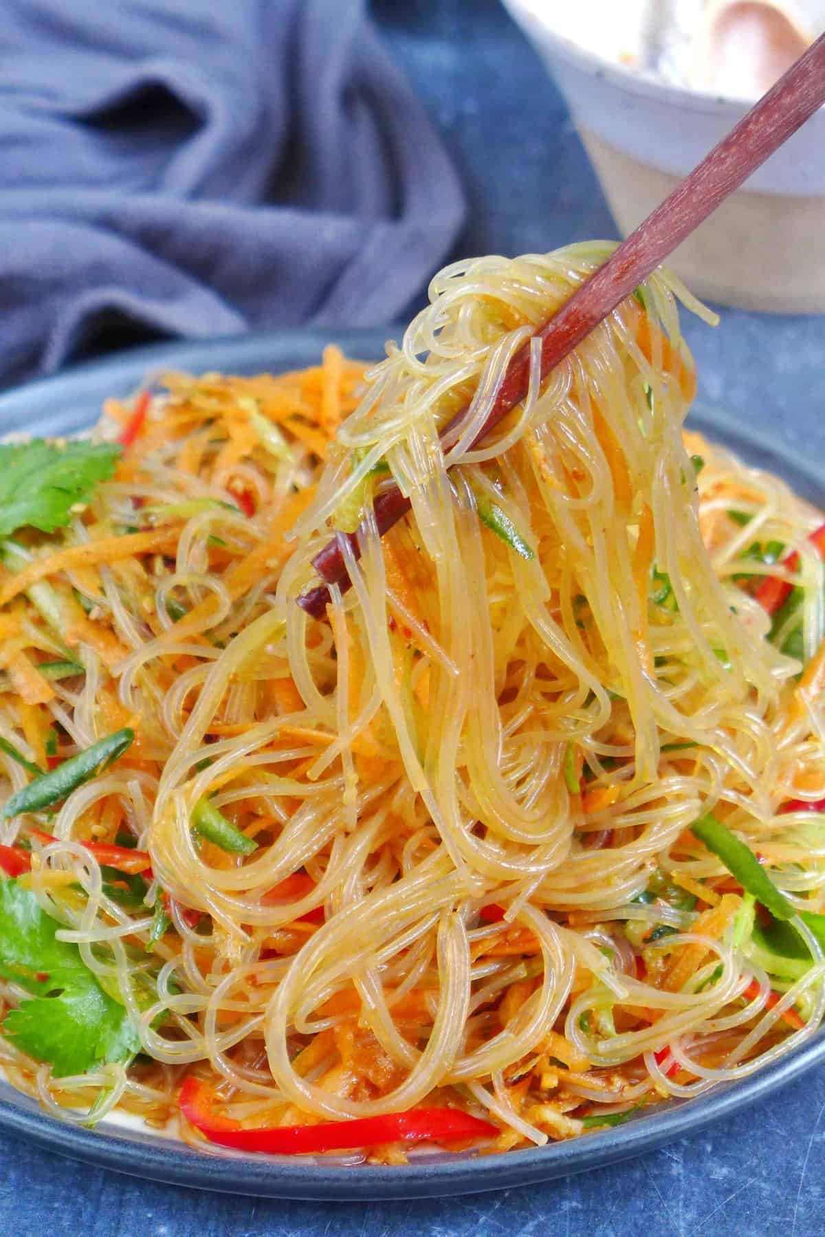 Lifting glass noodles with chopsticks.