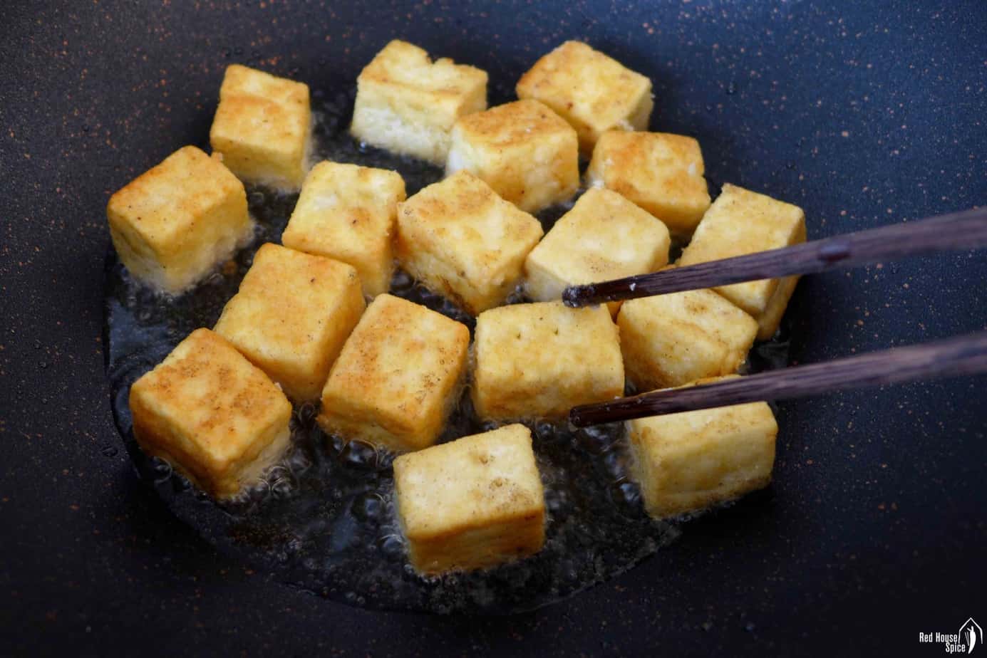 golden coloured tofu cubes in a pan