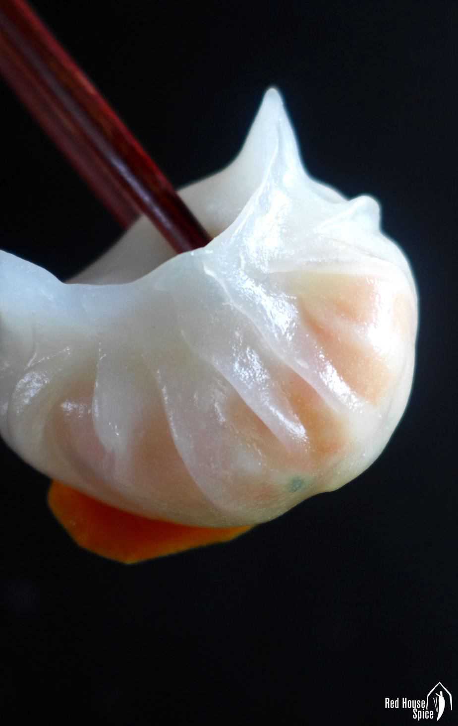 A Har Gow, crystal shrimp dumpling, held by chopsticks