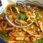 hot sour soup spooned out of a bowl with overlay text that says hot & sour soup