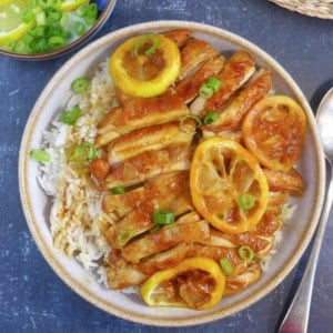 Chicken strips and lemon slices over a bowl of rice.