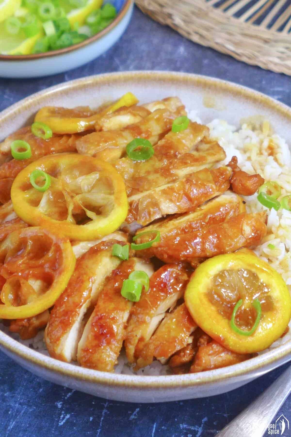 Sliced chicken and lemon over a bowl of rice.