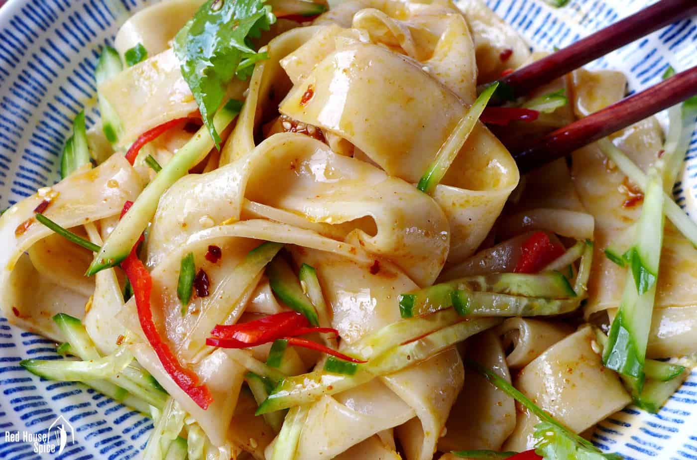 A close up shot of Liang Pi (cold skin noodles) coated with sauce and chilli oil.