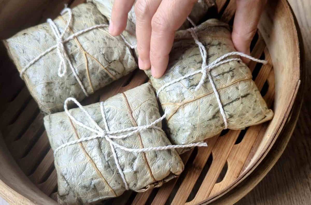 putting wrapped Lo Mai Gai into a steamer basket.