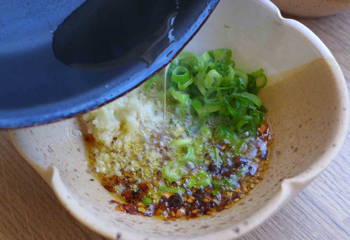 pouring hot oil over garlic, scallion, chili flake and sesame seeds.