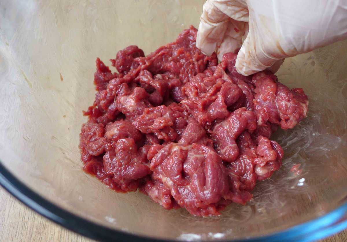 rubbing beef with marinade with hand.
