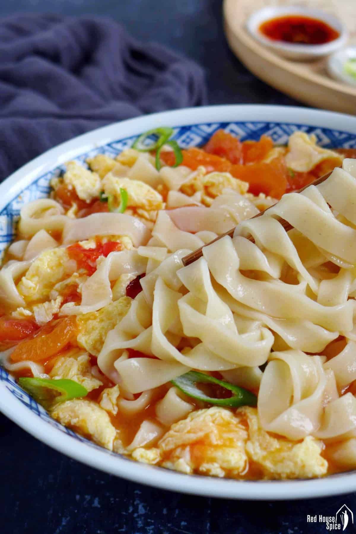 flat noodles held by chopsticks