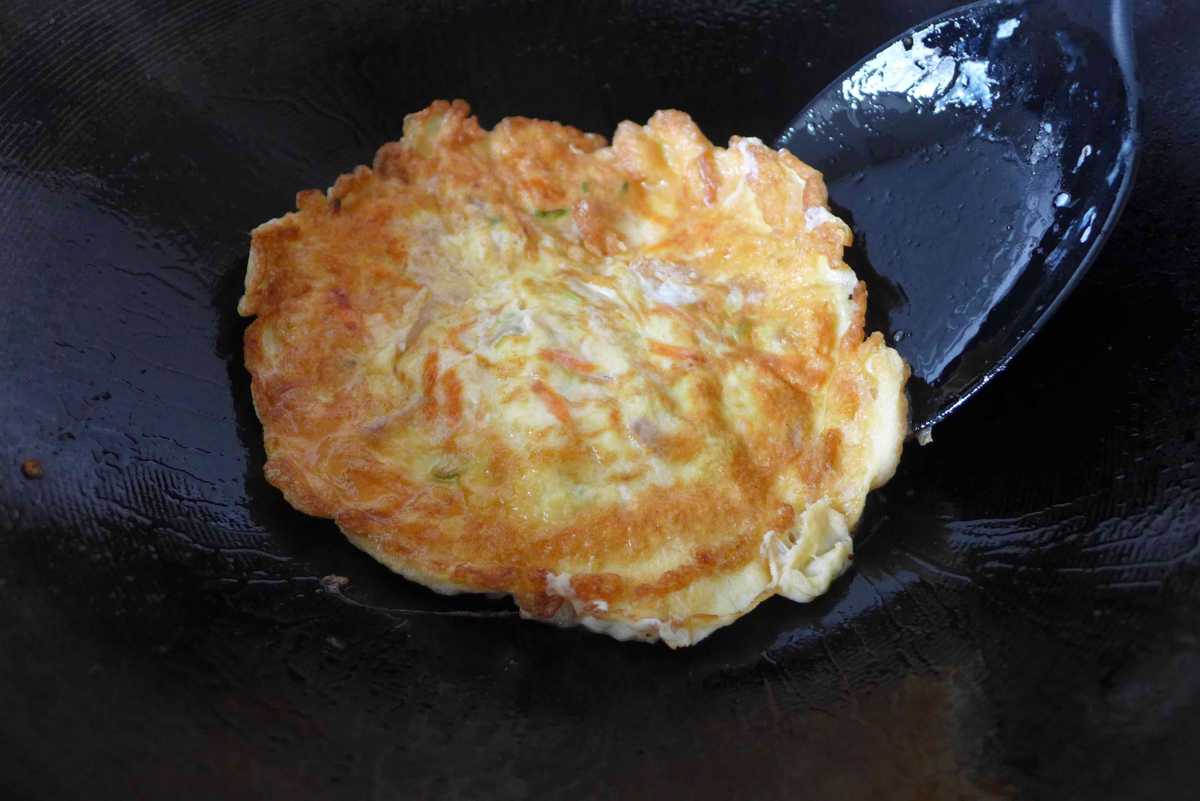 flipping an egg foo young with a spatula.