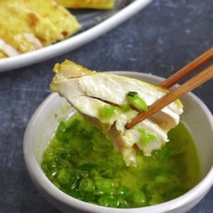 dipping a piece of salt baked chicken into the sauce.