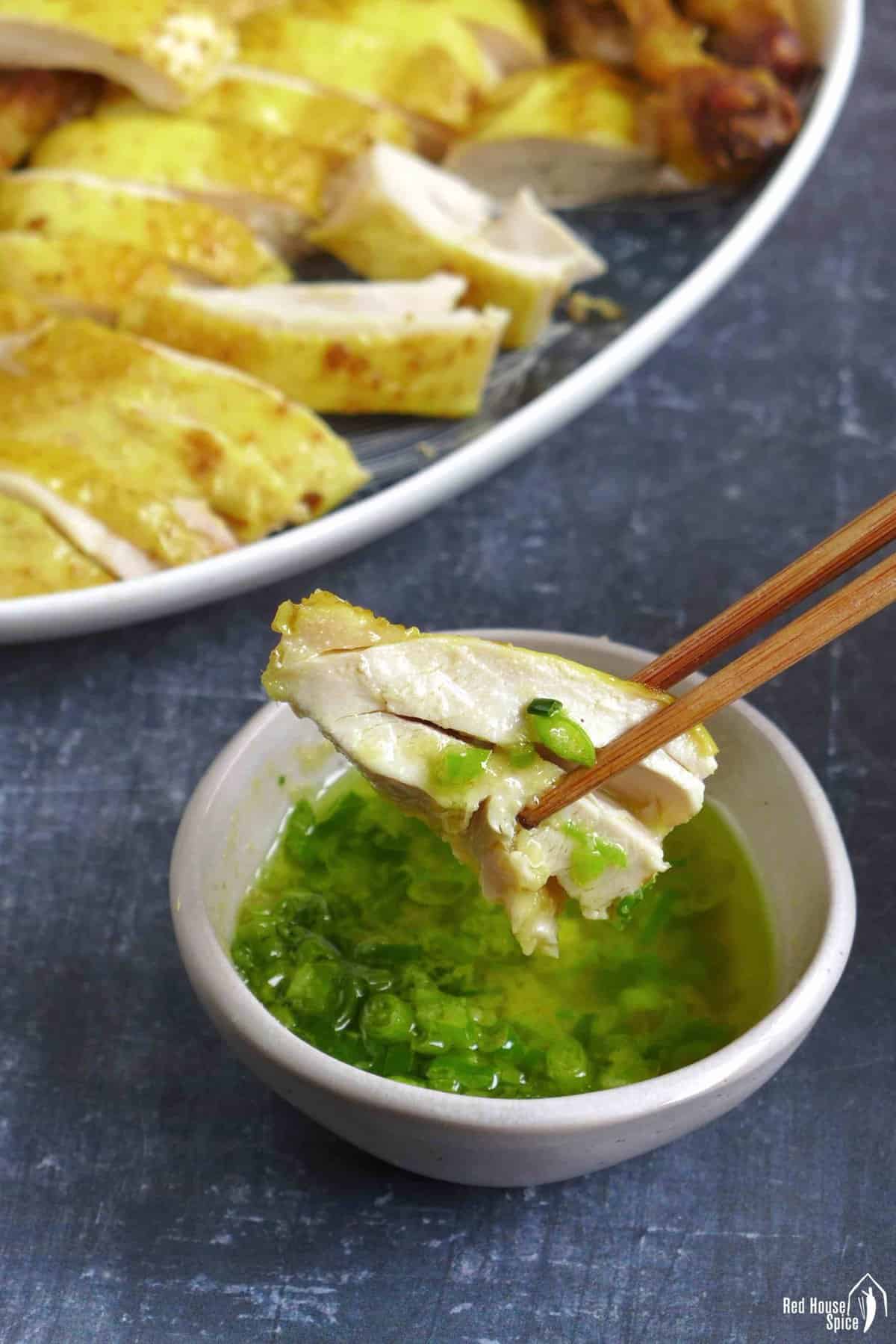 dipping a piece of chicken into the sauce.