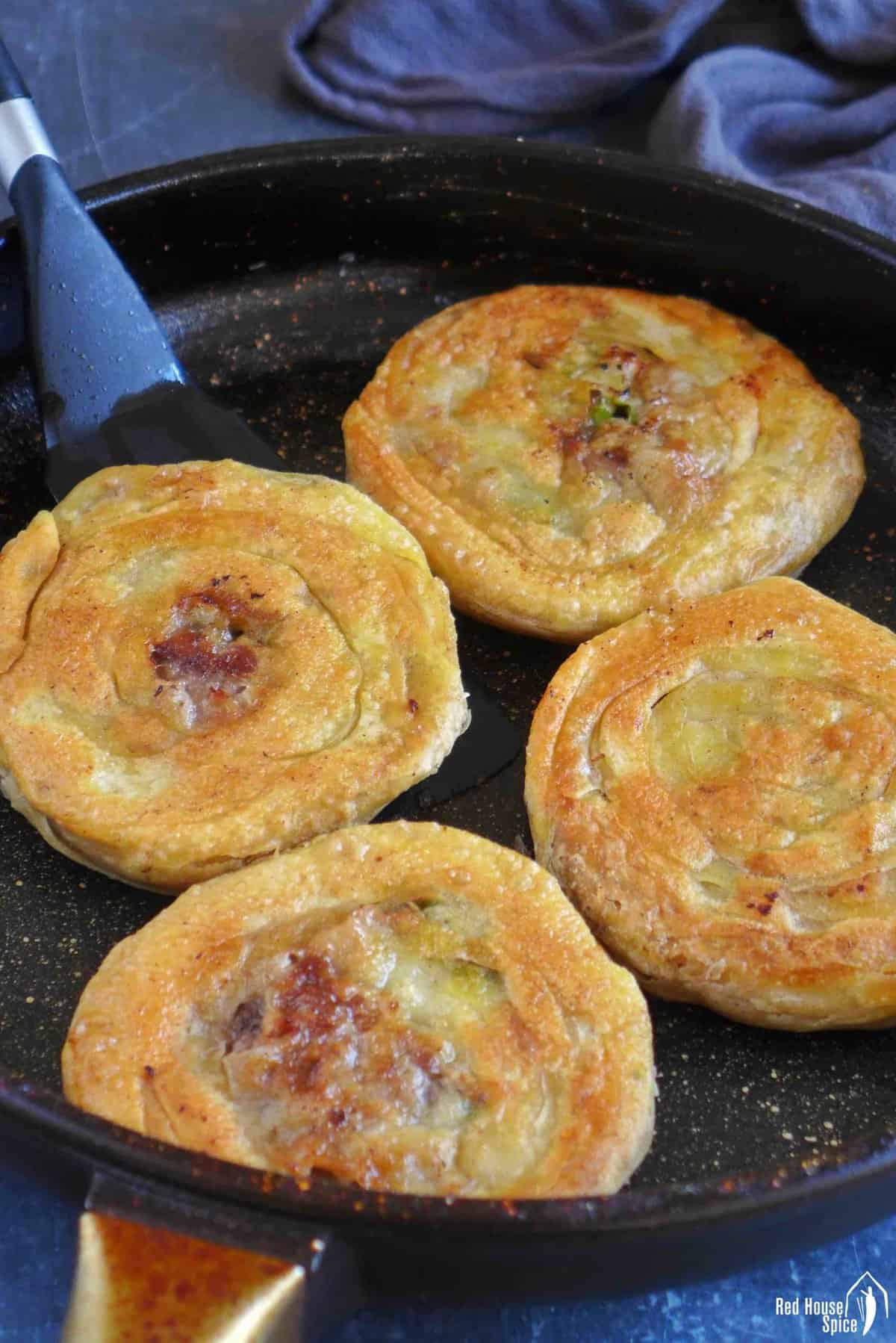 four beef stuffed flatbread in a skillet.