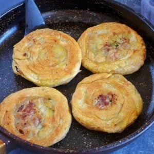 four beef stuffed flatbread in a skillet.