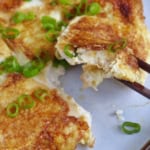 chopsticks picking up a piece of tofu omelet.