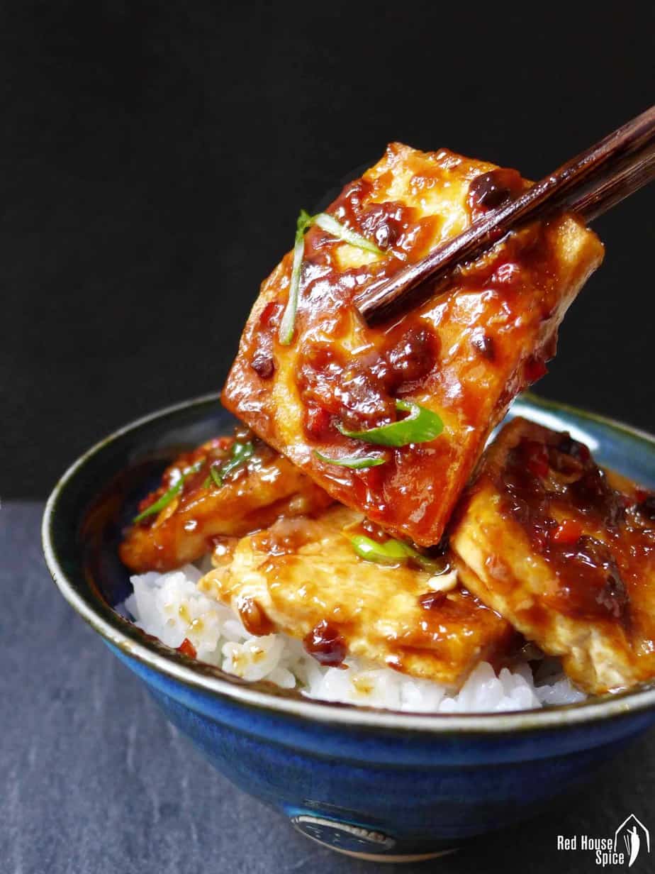 Chopsticks holding a piece of fried tofu