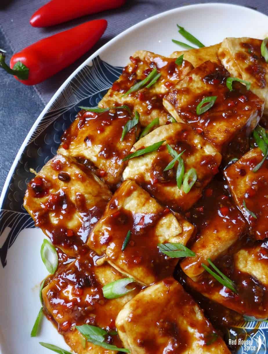 A plate of pan-fried tofu coated with garlic sauce