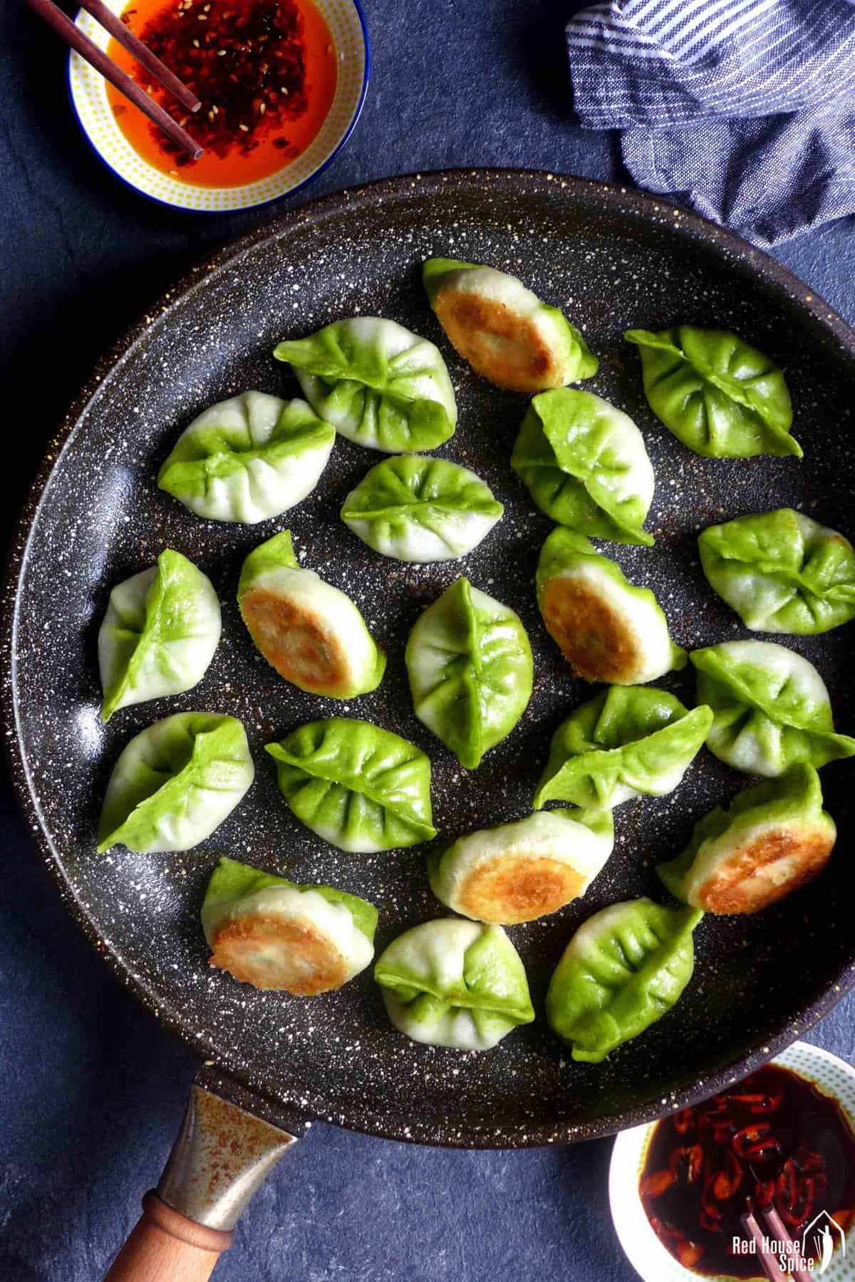 Pan-fried, bi-color, vegetarian dumplings in a pan.